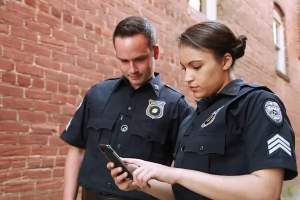 Two police officers looking at a cell phone.