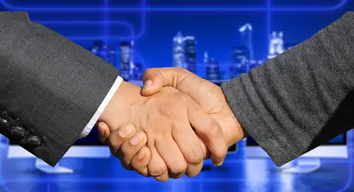 Two arms in business suits shaking hands.